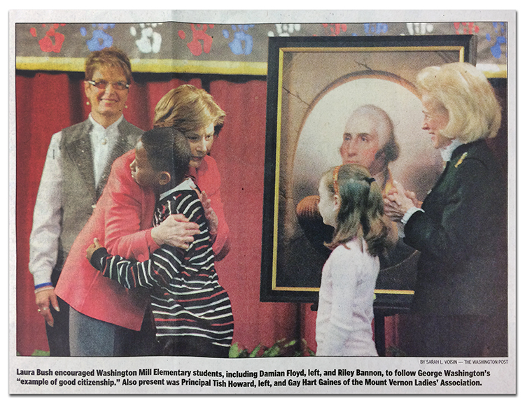 Newspaper photograph of First Lady Laura Bush hugging a student with the portrait of George Washington in the background. Behind her, on the left, is Principal Tish Howard. Another student and a representative from the Mount Vernon Ladies' Association are to the right of Bush. The image caption reads: Laura Bush encouraged Washington Mill Elementary students, including Damian Floyd, left, and Riley Bannon, to follow George Washington's example of good citizenship. Also present was Principal Tish Howard, left, and Gay Hart Gaines of the Mount Vernon Ladies' Association. 